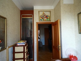 детский комод, встроенный шкаф у входной двери в детскую комнату с многочисленными яркими картинами на бежевых стенах квартиры художника в сталинке