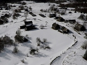 старые деревянные дома на больших участках под снегом в заброшенной деревне