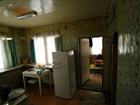 белый холодильник и стол с табуретом у окна кухни в зеленом цвете на даче СССР