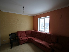 шкаф-купе, черное кресло, вишневоый угловой диван в комнате с яркими стенами дома с яркой кухней