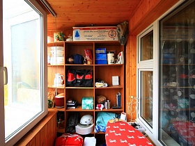 открытый деревянный шкаф с различными вещами и предметами, гладильная доска на застекленном балконе трехкомнатной актерской квартиры