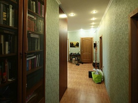 книжный шкаф в коридоре перед прихожей в современной просторной трешке