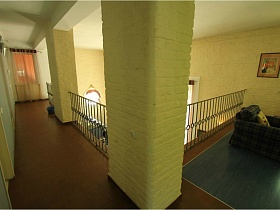 балкон второго этажа с резными металлическими перилами между большими желтыми колоннами в доме под съем
