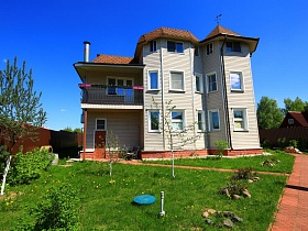 трехэтажный уютный дачный дом,выложен серым сайдингом,с большим открытым балконом над входной дверью