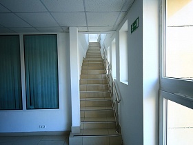 лестница с перилами и большими окнами вдоль стены офисного здания