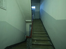 чистый ухоженный подъезд с серыми стенами и панелями, бетонной лестницей с перилами в жилом доме эпохи СССР