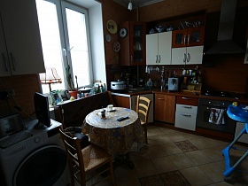 навесной шкаф над стиральной машинкой, круглый обеденный стол со стульями,мебельная стенка на кухне советской трехкомнатной квартиры