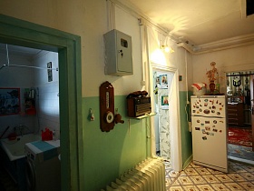 настенные чассы, старинный приемник и электросчетчик на стене между ванной комнатой и кухней в деревянной избе в деревне