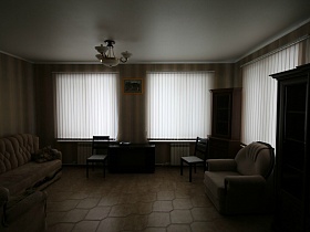 белая люстра на белом потолке в гостиной с полосатыми обоями на стенах пустого двухэтажного дома под съем в сосновом лесу