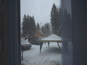 белая крыша летней палатки на снегу участка кирпичного добротного дома