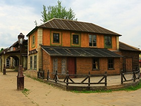 трактир в двухэтажном доме с пристроенной закрытой верандой и полукруглой открытой площадкой за деревянным дощатым забором в старом городке
