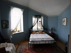 ковер у кровати и конусообразный белый потолок в спальне пустынного дома
