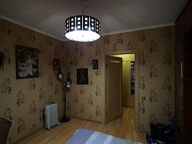 картины на стене с цветными обоями,торшер в стиле хай -тек, обогреватель в спальной комнате современной актерской трехкомнатной квартиры