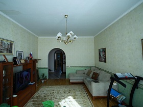 общий вид светлой гостиной с двухцветными стенами и арочным дверным проемом простой большой семейной квартиры в Марьино
