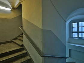 винтовая лестница с перилами на серых панелях отремонтированного жилого подъезда 12 с арочными сводами
