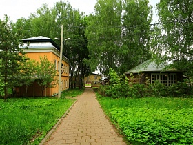 пешеходная дорожка, выложенная плиткой вдоль двухэтажного желтого деревянного домика в зеленом старом городке для съемок кино