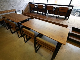 деревянные столы со стульями в зонированном просторном помещении уличного кафе с большими окнами вдоль проезжей городской дороги
