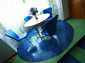 синие стулья с круглым столом на синем подиуме у окна