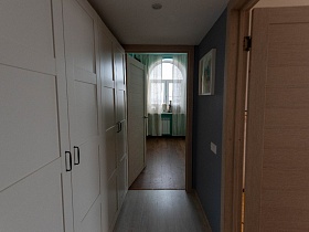 белые дверцы шкафов в голубой прихожей с картиной на стене современной квартиры в разных тонах