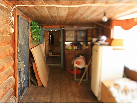 деревянная хлебница на белом холодильнике, шкаф с посудой, листы крагиса за старой зашитой входной дверью на веранду деревянного дома