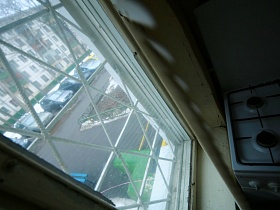 газовая плита у окна с решеткой съемной квартиры на первом этаже
