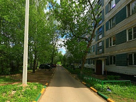 асфальтированная дорога с цветным бардюром вдоль жилой пятиэтажки в областном квартале