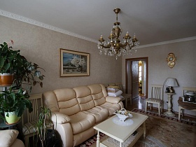 белый торшер с фигурной ножкой и деревянные молочные стулья у стены с часами в гостиной трехкомнатной квартиры врача