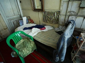 красный коврик у железной кровати с зеленым плассмасовым детским стульчиком в классичской даче