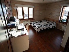 белое с черным покрывало на деревянной кровати бежевой спальни с белыми жалюзи на окнах просторного современного дома