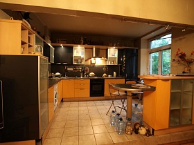 желтая кухня с встроенной стиральной машинкой, газовой плитой и черным холодильником в зонированной комнате разноплановой простой квартиры