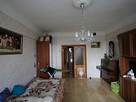 картина с цветами на стене над разложенным диваном , накрытым светлым покрывалом с цветами в гостиной квартиры сталинки