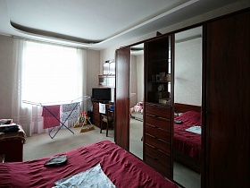 большой коричневый шкаф дл одежды с двумя зеркальными дверцами и многочисленными ящичками в спальне семейной трешки