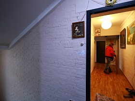 небольшая картина на белой кирпичной стене подъезда жилого дома над кнопкой звонка у открытой двери в лофт квартиру художника с картинами на стенах