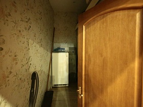 белый холодильник и пылесос в небольшой кладовке в трехкомнатной квартире