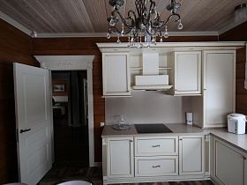 белая вытяжка над плитой в белой кухне с ящиками и шкафчиками в современном съемном коттедже