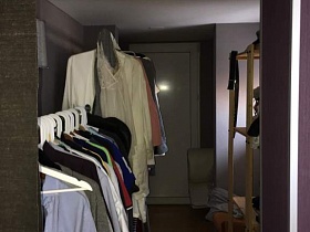 разноуровневые напольные вешалки с одеждой на белых тремпелях в гардеробной квартиры бухгалтера на девятом этаже