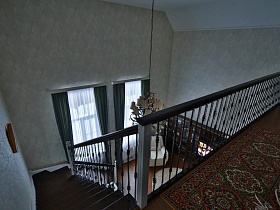 цветной ковер на площадке второго этажа с перилами и выходом на лестницу в гостиной современного кирпичного дома