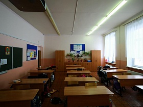 светлый школьный класс с партами в три ряда и стендами на стенах
