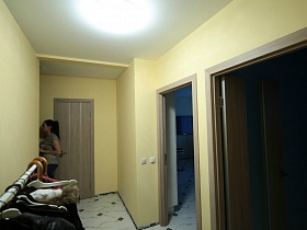 светлые стены прихожей с входными дверьми в комнаты молодежной квартиры Новостроя