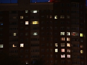 одинокие светлые окна квартир в современном многоэтажном жилом доме по улице Крылатские Холмы ночью