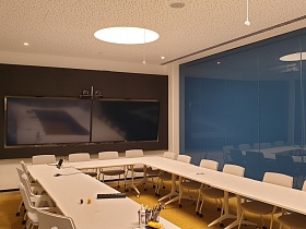  Большая переговорная комната с белым столом и мультимедйными стенами