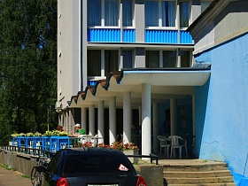 синяя машина и велосипед у ступеней лестницы с перилами на открытую террасу с волнообразной крышей гостиницы "Дубна" времен СССР