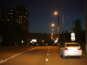 движущаяся машина по улице Крылатские холмы с подсвеченными дорожными знаками на обочине  в жилом квартале ночью