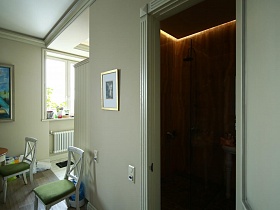 подсветка в потолке ванной комнаты с коричневой плиткой на стенах сквозь открытую дверь в девчачьей современной двухкомнатной квартиры
