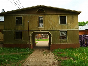 арочный переход в двухэтажном доме, требующем ремонта и дорожкой, выложенной плиткой в старом городке