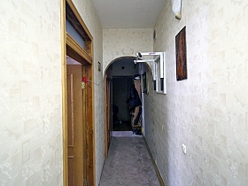 верхняя одежда на крючках шкафа, обувь у входной двери в просторную семейную квартиру с длинным светлым коридором с арочными дверными проемами в сталинском доме на шестом этаже