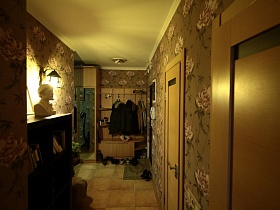 белый гипсовый бюст на темном шкафу с полками в оливковой прихожей с настенной вешалкой трехкомнатной актерской квартиры