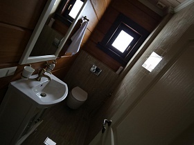 зеркало в белой рамке над белой раковиной со шкафчиком в ванной комнате с маленьким окном в съемном коттедже