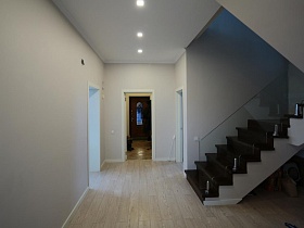 просторный белый холл с выходом на лестницу и в разные комнаты в загородном доме