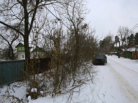 машина на проезжей снежной дороге вдоль дачных домов